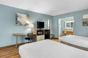 a hotel room with two beds and a desk and a tv at Quality Inn in Barbourville +32 photos