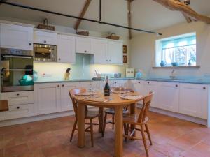 eine Küche mit weißen Schränken und einem Holztisch mit Stühlen in der Unterkunft Appletree Cottage Fressingfield in Fressingfield