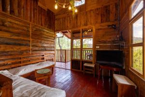 a bedroom with two beds and a television in a log cabin at Villa Verde in Perquín