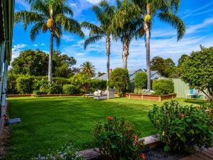 a yard with palm trees and a lawn with flowers at Wandew - Echuca Holiday Homes in Echuca +11 photos