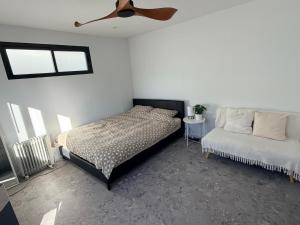 a bedroom with a bed and a couch and a ceiling fan at Sydney Studio with Private Bathroom & Kitchen in Revesby