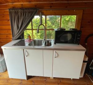 a kitchen with a microwave and a sink at Solberga red cottage in Solberga