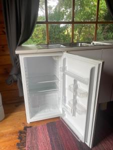 an empty refrigerator with its door open next to a window at Solberga red cottage in Solberga +16 photos