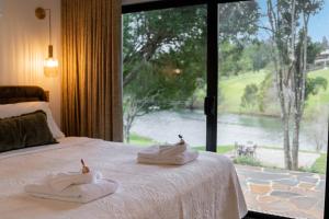 a bedroom with two towels on a bed with a large window at Lakes Edge Retreat in Yungaburra