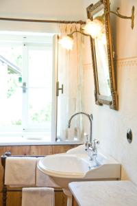 ein Bad mit einem Waschbecken, einem Spiegel und einem Fenster in der Unterkunft Haus Probst am See in Schondorf am Ammersee
