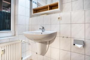 a white sink in a bathroom with white tiles at Ferienapartment 2 Heimathafen in Seedorf +26 photos