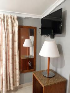 a room with a tv and a lamp and a mirror at 42 On Canterbury in Durban