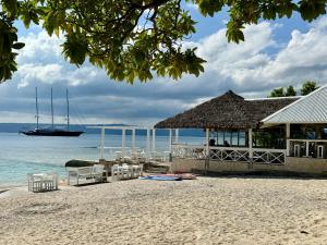a restaurant on a beach with a boat in the water at Coco Beach Resort in Port Vila +13 photos