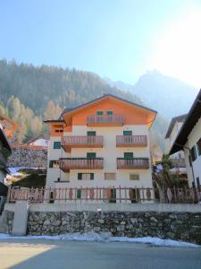 ein Apartmenthaus in Orange und Weiß in der Unterkunft Dolomites Seasons in Alleghe