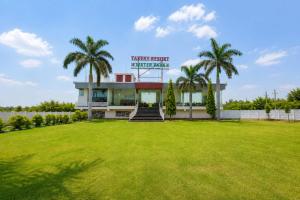 a building with palm trees in front of a field at Takery Resort in Chittaurgarh