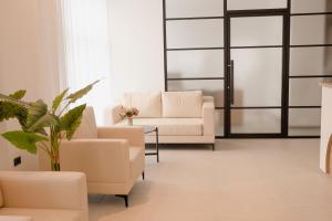 a living room with two white couches and a plant at Hotel Via Vitez in Vitez