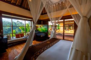 a living room with a canopy bed and a tv at Hanging Gardens of Bali in Payangan