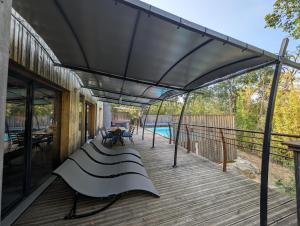 a covered deck with a bench and a pool at Villa Mammouth in Saint Alban Auriolles
