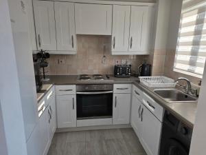 a kitchen with white cabinets and a sink at 2bdr Ground Floor Flat in Edmonton free Parking and WiFi in Ponders End