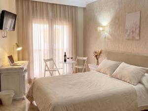 a bedroom with a white bed and a table with chairs at Hotel Playa del Carmen in Barbate +25 photos