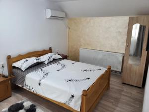 a bedroom with a bed with a white comforter at Pensiunea Casa Deny in Novaci-Străini