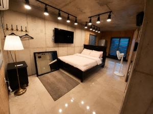 ein Schlafzimmer mit einem Bett, einem Fernseher und Lampen in der Unterkunft 수스테이 펜션 in Seogwipo