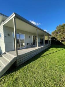 a porch of a house with a grass yard at Bach At 45 in Ahipara