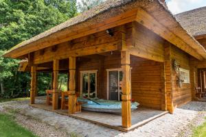 a log cabin with a large porch and a porch at Močiutės sodyba in Latežeris