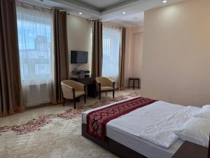 a bedroom with a bed and a desk and chairs at Tsetsenkhangai Hotel in Ulaanbaatar