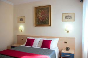 ein Schlafzimmer mit einem Bett mit roten und weißen Kissen in der Unterkunft Città Eterna Guest House in Rom