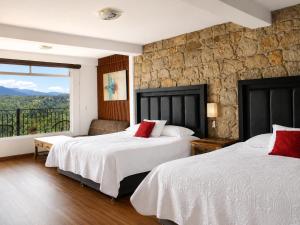two beds in a hotel room with a large window at Vista Zacatlan Hotel in Zacatlán