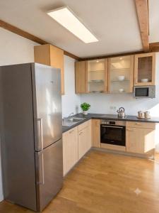 a kitchen with a stainless steel refrigerator and wooden cabinets at Central Starnberg and surrounded by nature in Starnberg