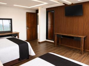 a hotel room with a bed and a flat screen tv at Vista Zacatlan Hotel in Zacatlán