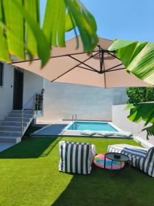 a pool with two chairs and a table and an umbrella at Sunset Horizon Lagonisi in Kalívia Thorikoú