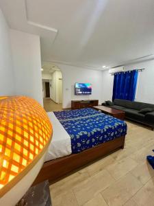 a bedroom with a bed and a couch and a tv at Tchaopremium in Lomé