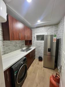 a kitchen with a stainless steel refrigerator and wooden cabinets at Tchaopremium in Lomé