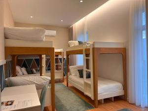 a room with three bunk beds and a table at Pedra de Sal Hostel & Suites in Rio Maior