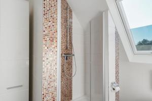 a bathroom with a shower with a mosaic tile wall at Fewo Tief Blick in Dornum +13 photos