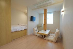 a bedroom with a bed and a table and two chairs at Connected Hotel Nonhyeon in Seoul