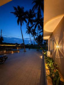 a night view of a building with palm trees at Kadapu stay in Udiyāvara