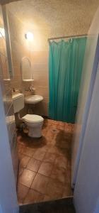 a bathroom with a toilet and a sink and a green shower curtain at Атлас in Byala