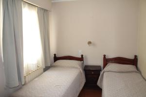 two twin beds in a room with a window at Cabo Vírgenes in Río Gallegos