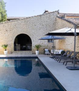 a pool with chairs and umbrellas next to a building at Le Mas de Sòmi in Aubais