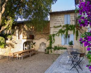a courtyard of a house with a bench and tables at Le Mas de Sòmi in Aubais
