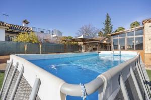 a swimming pool with chairs and a house at Rural El Santiscal in Arcos de la Frontera