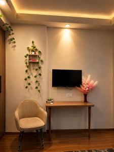 a living room with a desk and a tv and a chair at The Sky cabin in Greater Noida