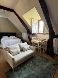 a bedroom with a bed and a couch and a table at Le Moulin de l`Epinay in Sainte-Beuve-en-Rivière