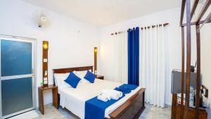 a bedroom with a bed with blue pillows and a tv at Sansevieria Homestay in Sigiriya