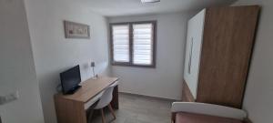 a room with a desk with a television and a window at Sa Omu de S'Olia in Tertenìa