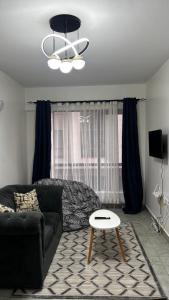 a living room with a black couch and a table at Authentic Galore in Ongata Rongai 