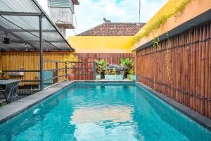 a swimming pool in a backyard with a wooden fence at Bali Bay By Urban Haven in Sanur