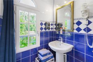 a blue tiled bathroom with a sink and a mirror at Les Soliers in Étretat