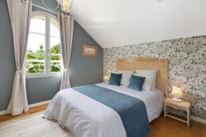 a bedroom with a bed with a blue blanket and a window at Les Soliers in Étretat