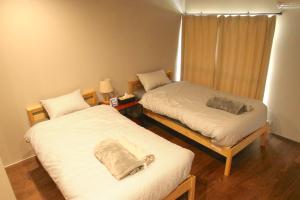 a room with two beds and a lamp and a room with at The Glow Omachi B棟 in Omachi