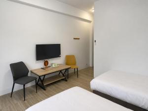 a room with a bed and a desk with a tv at Hai Jing Man Lu B&B in An-hsia